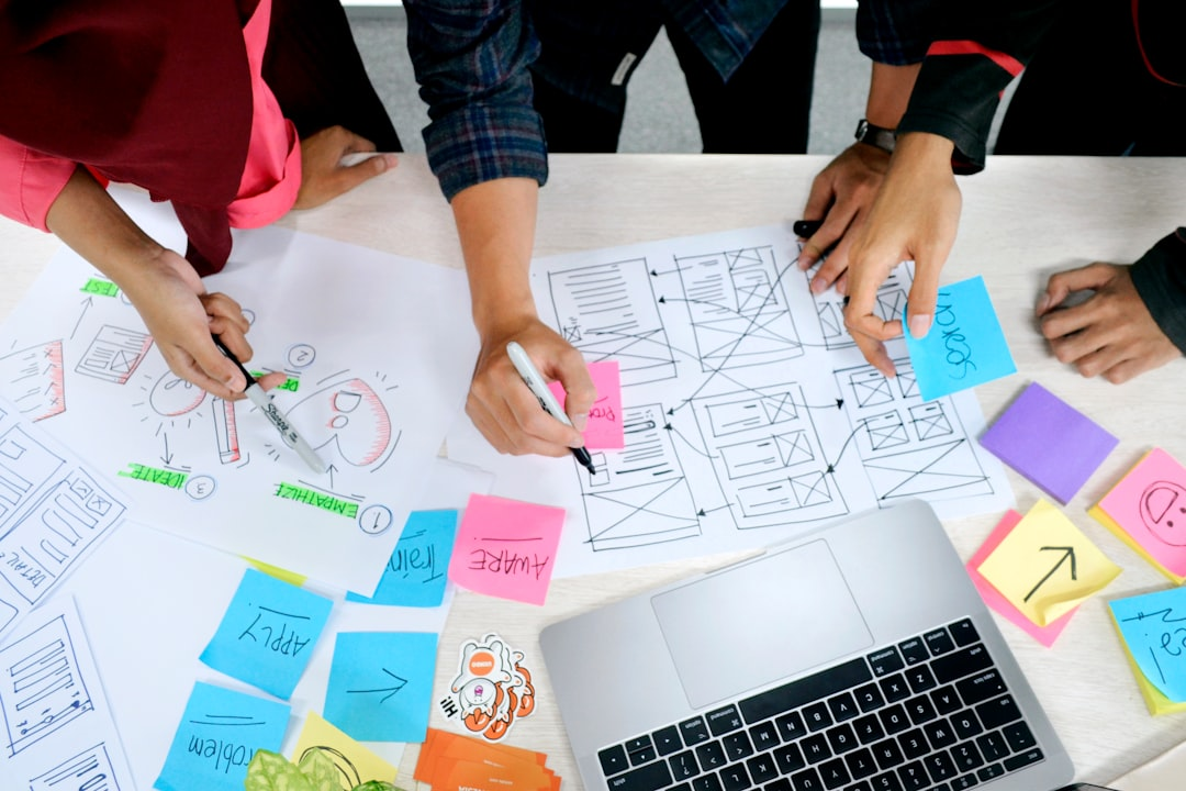 Overhead photo of a team sketching layouts and notes around a laptop, representing collaborative design work shaped by structure and constraints.